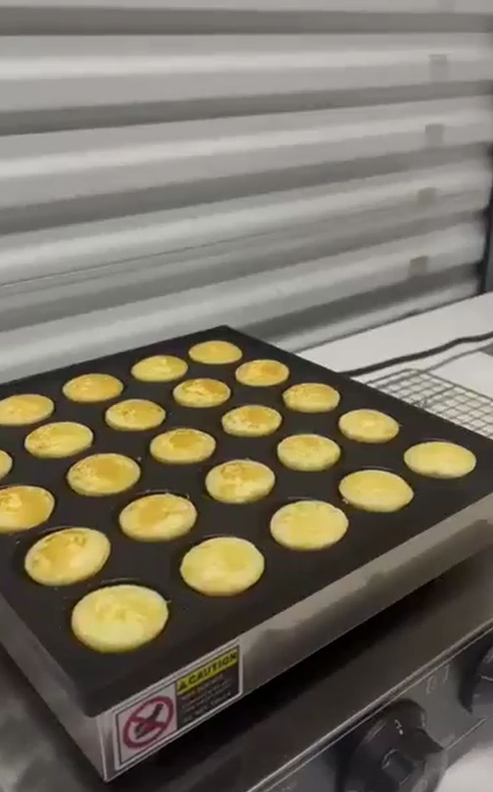 Máquina cocinando 25 mini panqueques dorados simultáneamente