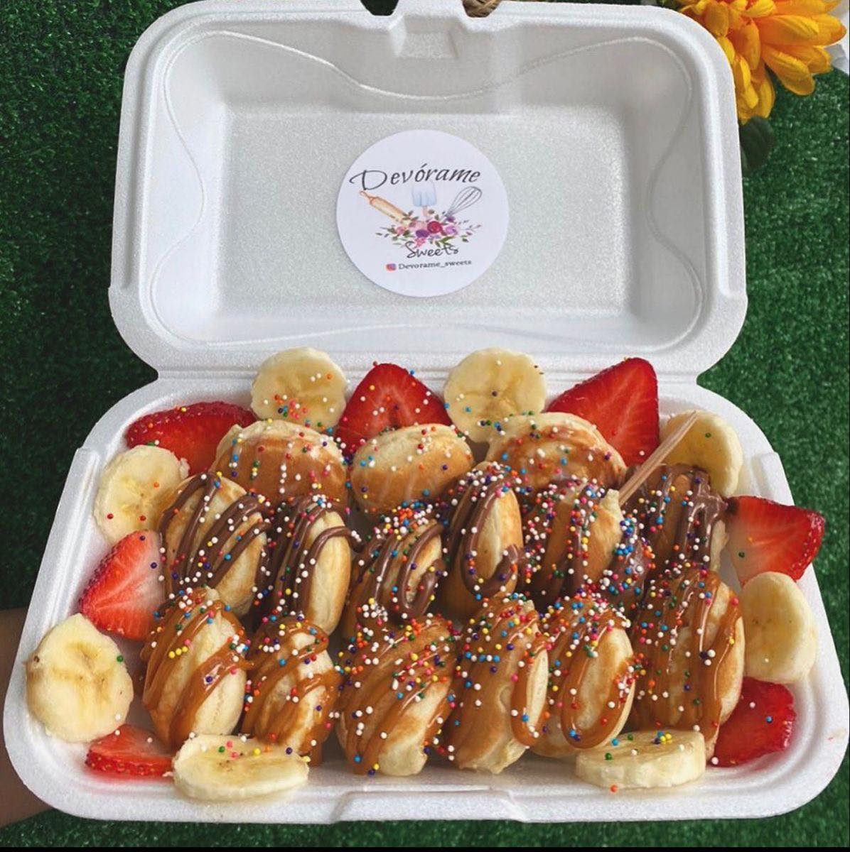 Mini panqueques terminados con chocolate, frutas y sprinkles servidos en caja